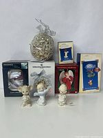 Group photo showing various boxed and loose vintage Christmas ornaments including Precious Moments figurines and packaged glass ornaments