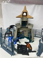 Full view of the main building, fences, turrets, dinosaur figures, and sign pieces arranged inside fenced area