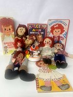 Photo showing entire lot with dolls, books, paper dolls, and porcelain music box visible