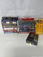 Stack of sealed VHS tapes including Twister, Shania Twain Live, Hunters, Independence Day, Dances With Wolves, Forces of Nature, The Mighty, Blues Brothers 2000, and Indiana Jones Trilogy not sealed.