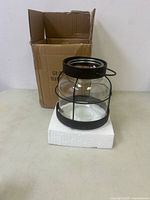 Full view of the glass vase inside its original cardboard box with white foam base.