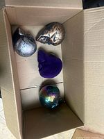 Box containing three decorative skulls in different colors and textures.