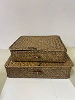 Two stacked woven rectangular storage baskets with lids in coffee color shown closed from a front angle
