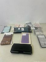 Overview shot of all cell phone cases arranged on a table, showing variety in colors, packaging, and styles.