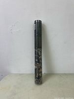 Full view of the wallpaper roll showing it tightly rolled with dark tapestry design visible.