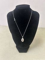 Full view of the necklace displayed on a black bust stand showing the chain and closed locket pendant.