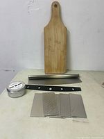 Wooden cutting board, pizza cutter, sharpening stones, cutting board wax arranged on table