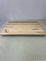 Top view of the La Flambee wooden cutting board showing wood grain and logo.