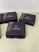 Six black and gold Laavoo hair extension boxes closed and displayed on table.