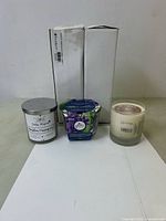 Three candles on white paper with background boxes: Joseph and Child Golden Pineapple, Glade Lavender Lilac, and White Sheep Vanilla Soy candle.
