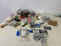Overview of lot on table including shackles, card multi-tools, utility blades, wire spool, clamps, chains, and small hardware items.