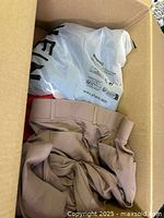 Box with beige women's pants, plastic bag with Shein branding inside the box