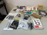 View of multiple new electronic accessories arranged on a table including cables, adapters, chargers, and packaged items