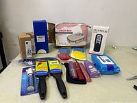 Full view of assorted new household items including lunch box, brushes, lipsticks, wipes, and sterilizer