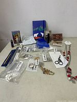 Photo showing overview of lot items including tarot card decks, blue notebook, crystals, packaged jewelry components, and accessories on table