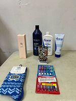 Lot items displayed on table showing all new personal care and household products including the Redken and Renew bottles, socks, decorative ceramic house, and toothbrush pack