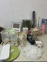 Wide view of miscellaneous new household items including kitchenware, decor frame, and party cups packed in a box.