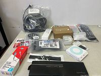 Table with various small electronic items including remotes, cables, MP3 player, and accessories spread out for identification.