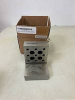 Photo showing the angle plate standing adjacent to the original cardboard box with the product label visible.