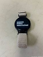 Samsung Galaxy Watch Active2 showing brand and model on screen, attached to light fabric strap with zigzag pattern.