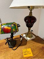 Two lamps on wooden table, note with item details visible.