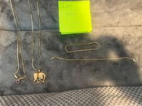 All 4 jewelry pieces laid out on gray fabric background showing two necklaces with pendants and two bracelets.