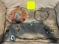 All jewelry items laid out: two choker necklaces, pair of earrings, beaded hair clasp, glass ring, long pendant necklace, small pin