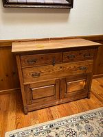 Full view of antique wooden cabinet showing drawers and doors with handles.
