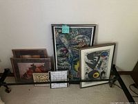 Photo shows all six framed art pieces leaning against the wall, various sizes and styles visible.