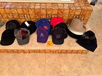 Overview of all hats laid out on tiled step, showing various styles including knit hats, baseball caps, and fedoras.