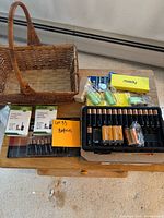 Overview of all batteries laid out on wood surface along with woven basket and mix of opened battery packs.