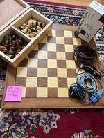 Full view of chess board with chess pieces in wooden box to one side, cables beside the board, and the Digital Game Timer box to top right.