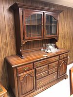 Full view of dark wood dining hutch with glass fronted top cupboard and brass handles.