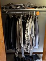 Full view of assorted men's clothing hanging on a rack, mostly suits and shirts in various colors and styles.