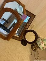 Four mirrors and a table lamp arranged on carpet; shows variety and condition of lot including visible wear and cord on lamp.