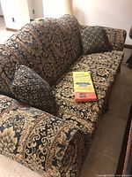 Full view of the Mediterranean style blue/red brocade sofa with two matching throw pillows and furniture sliders placed on cushion.