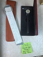 Starrett dial caliper visible with dial, in foam-lined case next to Deci-Lon slide rule with cursor and orange case.