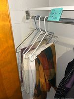 Photo showing five tablecloths hanging on plastic hangers in a closet, displaying various colors and styles including plaid and lace fabrics.