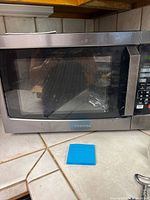 Front view of Toshiba stainless steel microwave on countertop showing door and control panel reflection.