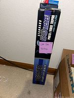 Photo of the closed original box for a Bower 59 inch Steady Lift Series Photo Video Tripod, model VT51200, standing upright on carpet against a wall.