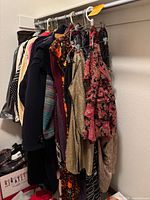 Rack of women's clothing items hanging on hangers, showing a variety of garments including dresses, sweaters, skirts mostly in size large.