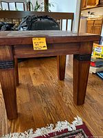 Photo showing the low profile and leg detail of the cherry wood side table with a solid wood frame and carved horizontal bands on legs.