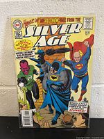 Comic book front cover showing Batman, Superman, Green Lantern and other characters in a dynamic scene, the title 'Silver Age' prominently displayed.