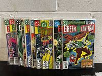Photo of 11 Green Lantern comic books #148 to #158 stacked upright inside plastic sleeves, showing front covers with vibrant cover art and numbering.