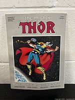 Paperback graphic novel titled 'The Mighty Thor' with Thor in his costume on the cover against a space background.