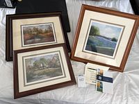 Three framed artworks on bed showing overall condition and matting