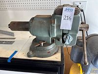 Side view of green swivel-base bench vise mounted on bench