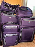 Group shot showing all five matching purple American Tourister pieces