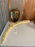 Vase and tusk side by side on table