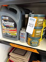 Front view of shelf with Prestone jug, three Bendix grease tins, silver metal can